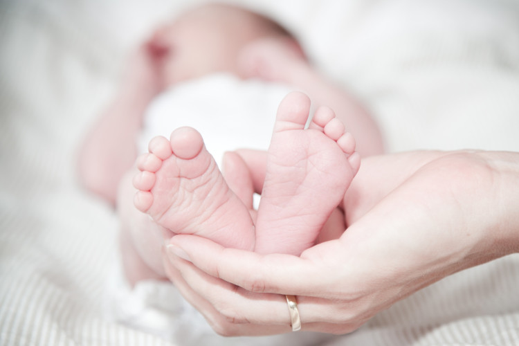 Image of baby's feet being held with adult hands